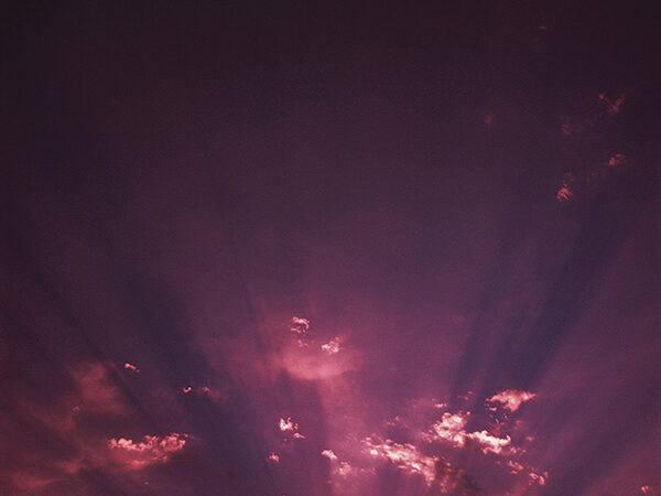 Vibrant sunset with pink and purple clouds, sun rays spreading across the evening sky.