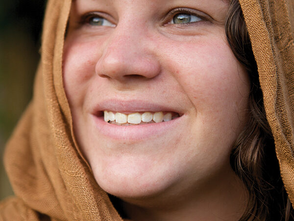 Smiling woman wearing a brown scarf, looking upward with a serene expression.