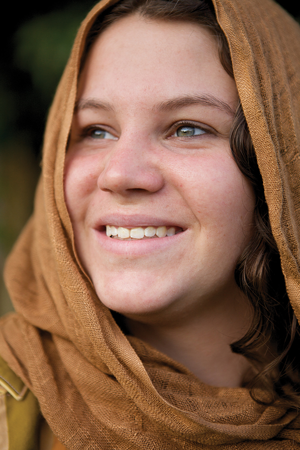 Smiling woman wearing a brown scarf, looking upward with a serene expression.