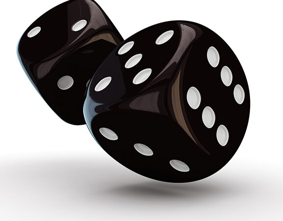 Two black dice with white dots tumbling through the air, casting a shadow on a white surface.