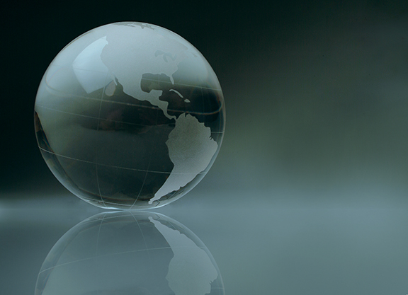 Transparent globe with etched continents on a reflective surface, symbolizing global connectivity and international reach.