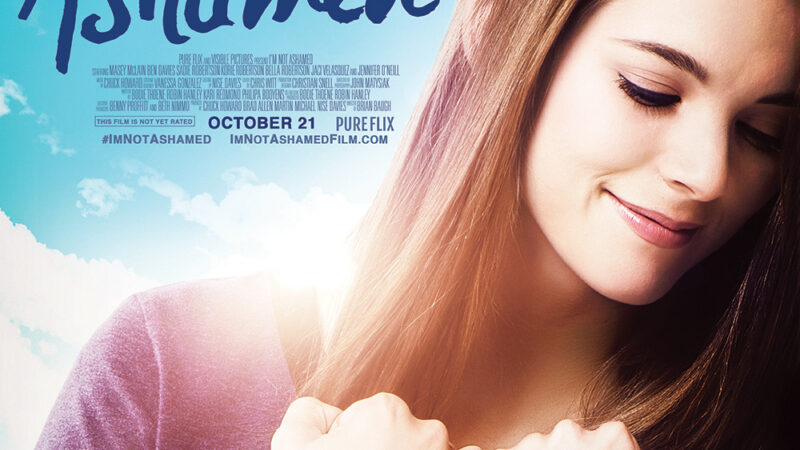 Film poster for I'm Not Ashamed, featuring a smiling woman holding a book with Columbine HS Rebels '99.
