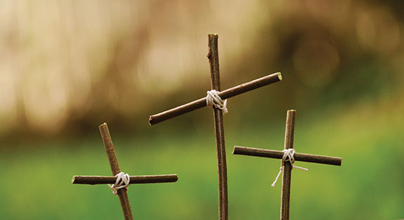 Three wooden crosses on a grassy background, symbolizing faith and spirituality.