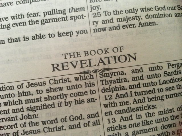 Close-up of a Bible open to the Book of Revelation, featuring text from the New Testament scriptures.