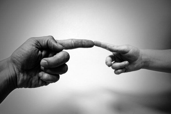 Two hands reaching towards each other in black and white, symbolizing connection and unity.