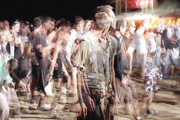 Blurred crowd at a nighttime outdoor music festival, creating a sense of movement and energy.