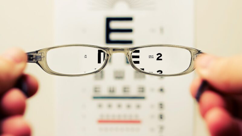 Close-up of eyeglasses focusing on an eye chart, highlighting vision clarity and eye care.