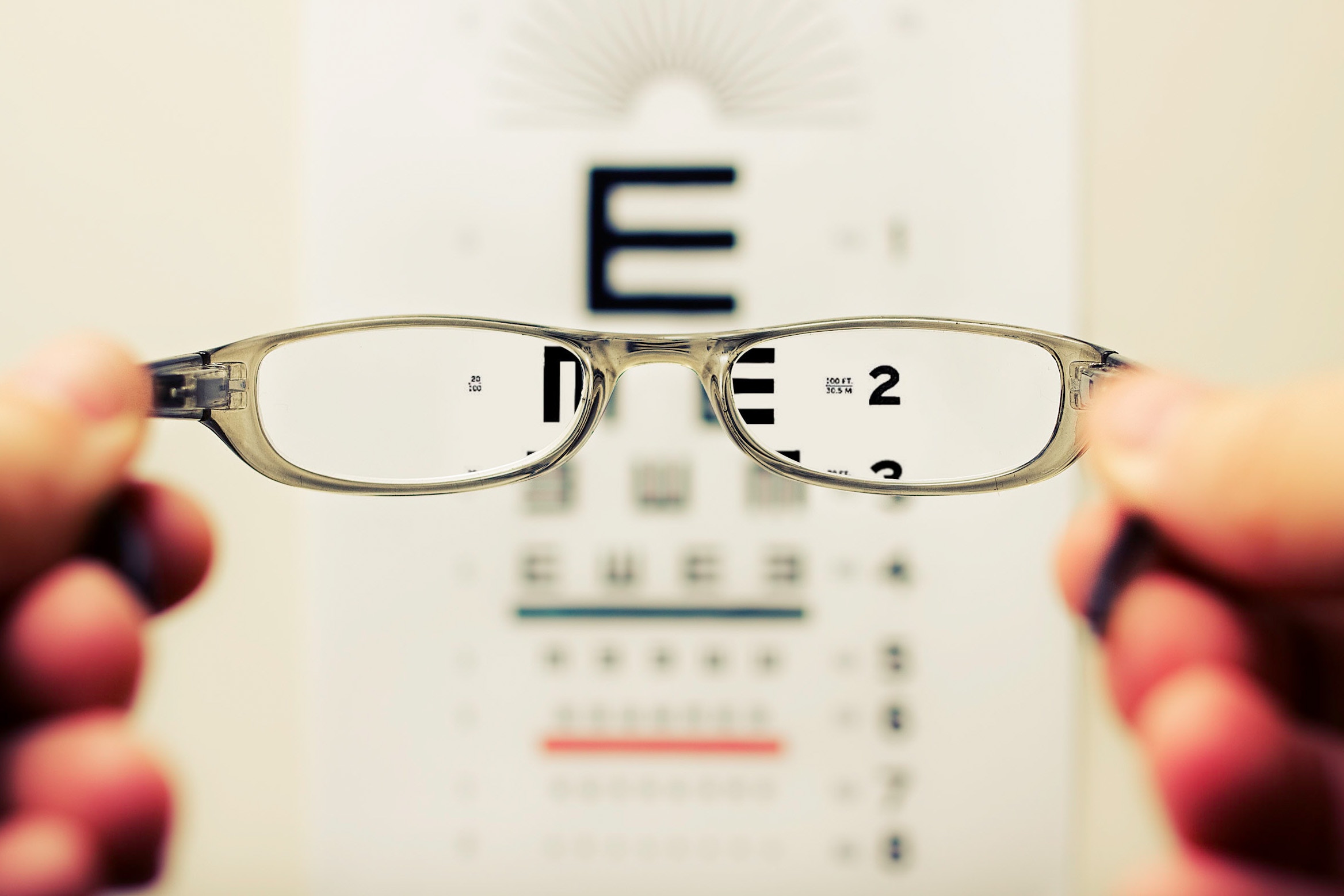 Close-up of eyeglasses focusing on an eye chart, highlighting vision clarity and eye care.