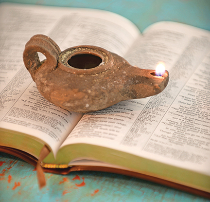 Ancient oil lamp illuminating open book with text, symbolizing wisdom and enlightenment against a blue background.