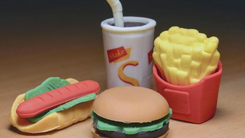 Toy fast food items: hamburger, hot dog, fries, and drink on a wooden surface. Fun and colorful play set.