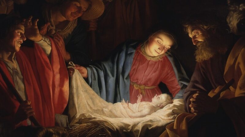 Nativity scene with the holy family and shepherds around baby Jesus in a manger.