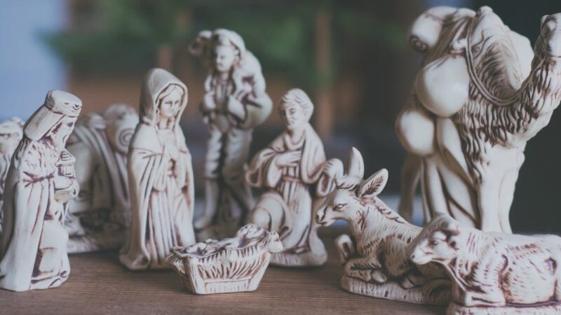 Nativity scene figurines with Mary, Joseph, baby Jesus, and animals on a wooden table, capturing a serene holiday moment.