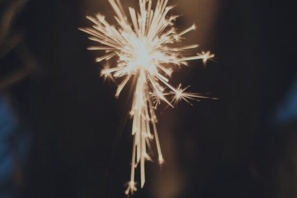 Close-up of a lit sparkler shining brightly in the dark, creating a festive and celebratory atmosphere.