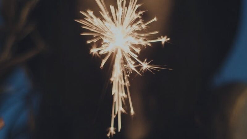 Close-up of a lit sparkler shining brightly in the dark, creating a festive and celebratory atmosphere.