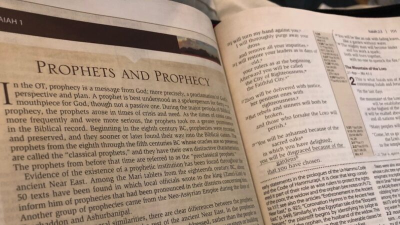 Open Bible showing text on prophets and prophecy from Isaiah 1, discussing biblical themes and interpretations.