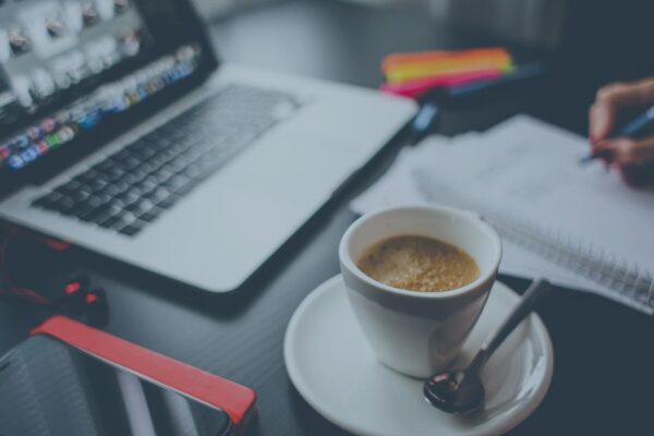 Laptop, coffee, and notepad on desk for productive work session.