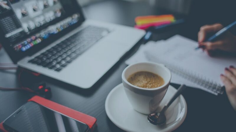 Laptop, coffee, and notepad on desk for productive work session.