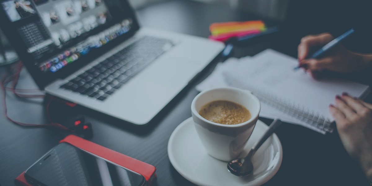 Laptop, coffee, and notepad on desk for productive work session.