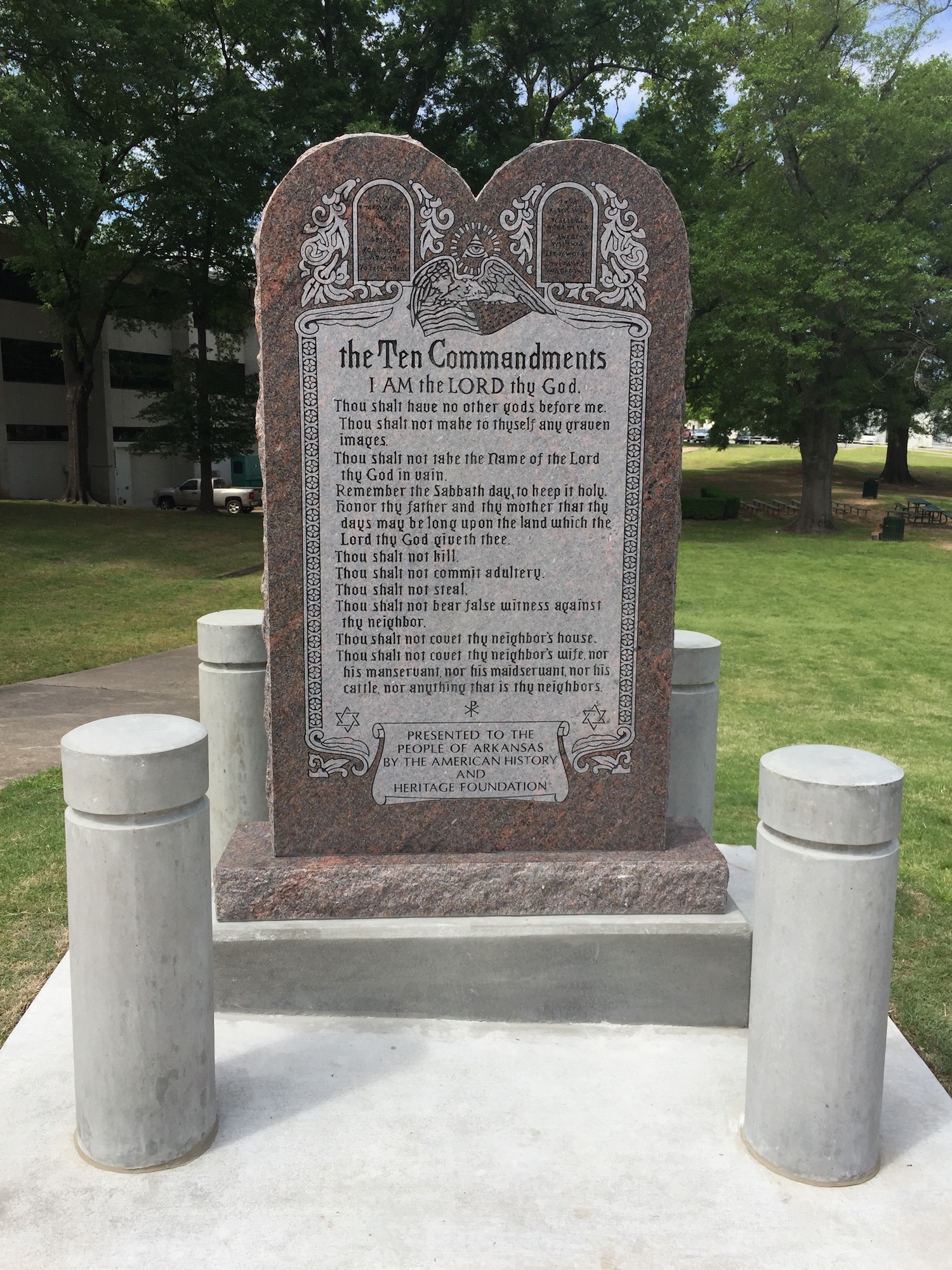 Granite Ten Commandments monument in a park setting with green trees in the background.