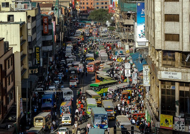 Busy urban street scene with heavy traffic and crowded sidewalks, showcasing vibrant city life and bustling activity.