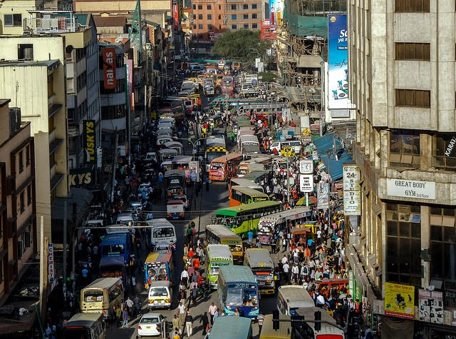 Busy urban street scene with heavy traffic and crowded sidewalks, showcasing vibrant city life and bustling activity.