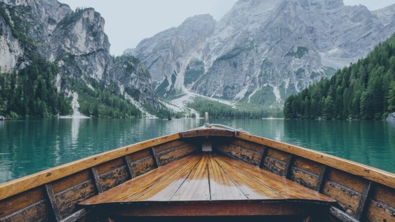 Wooden boat on a serene lake surrounded by majestic mountains and lush forests. Ideal for nature and travel inspiration.