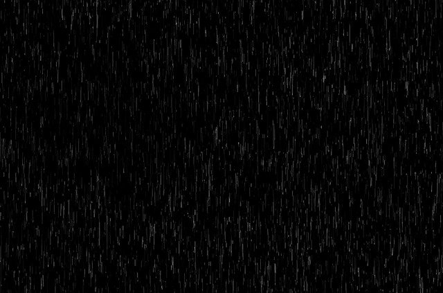 Heavy rainfall at night, with streaks of rain against a dark background.