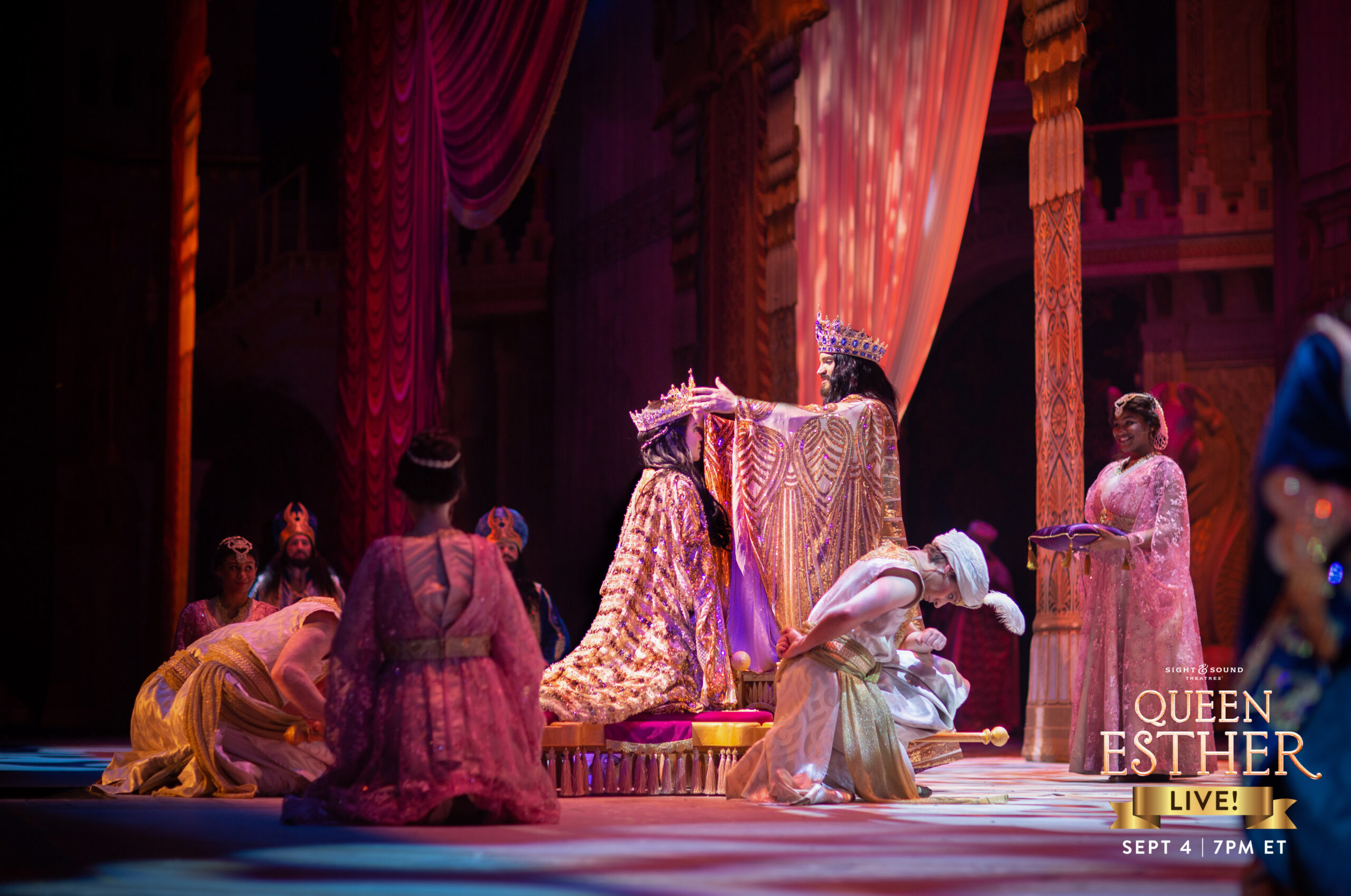 Theatrical scene from Queen Esther featuring actors in royal costumes on stage, with elaborate set design.