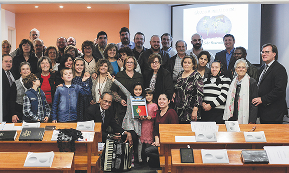 A group of people at a conference room, smiling and posing for a group photo in front of a presentation screen.