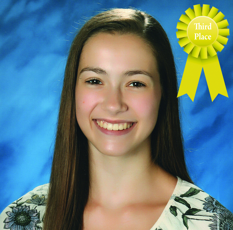 Smiling person with long hair and floral top, awarded third place with a yellow ribbon on a blue background.