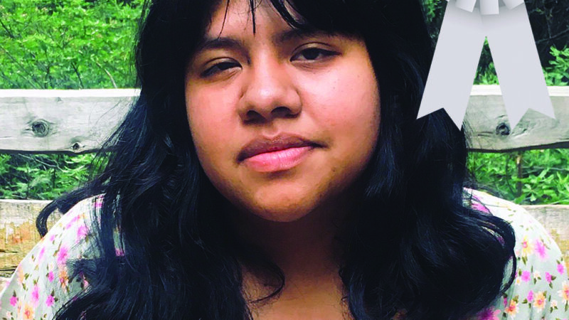 Young person outdoors with a floral top and an Honorable Mention ribbon.