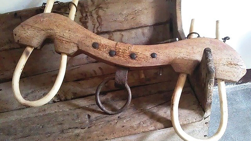 Wooden yoke for cattle on rustic wooden bench, showcasing traditional farming equipment.