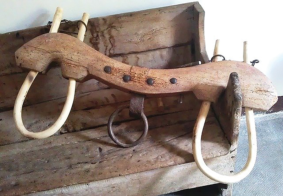 Wooden yoke for cattle on rustic wooden bench, showcasing traditional farming equipment.