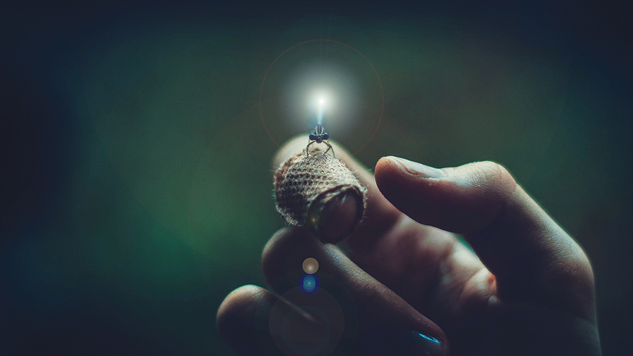A close-up of a hand holding a glowing light on the index finger, creating a magical, mystical atmosphere.