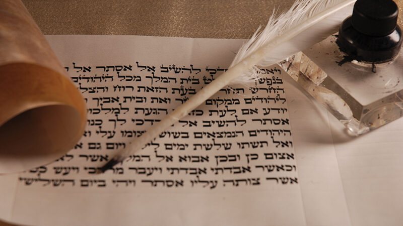 Ancient Hebrew scroll with quill and ink, symbolizing traditional writing and historical documentation.