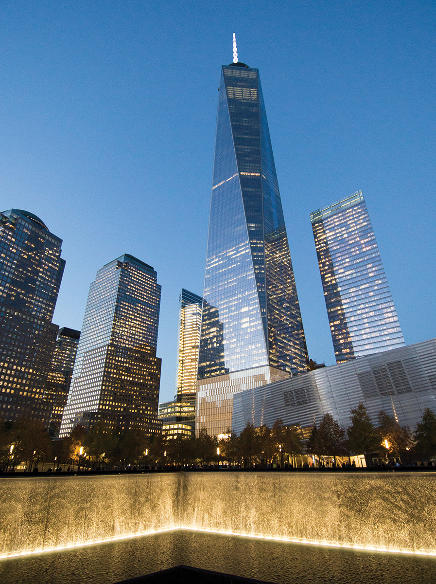 Skyscrapers at sunset with a reflecting pool in New York City, showcasing modern architecture and urban landscape.