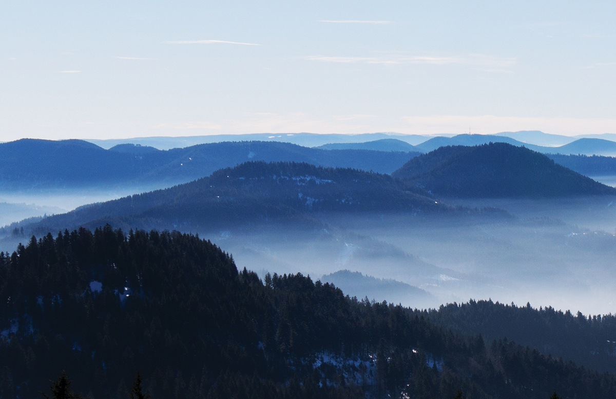 Scenic view of misty mountain ranges under clear blue sky.