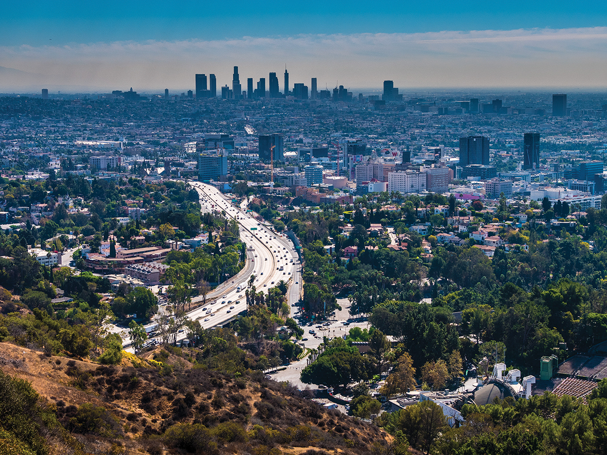 Aerial view of Los Angeles skyline with busy freeway and urban landscape on a clear day.