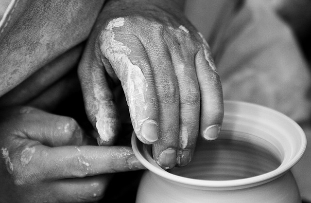 Hands shaping clay on a pottery wheel, showcasing creativity and craftsmanship in ceramics. Black and white close-up.