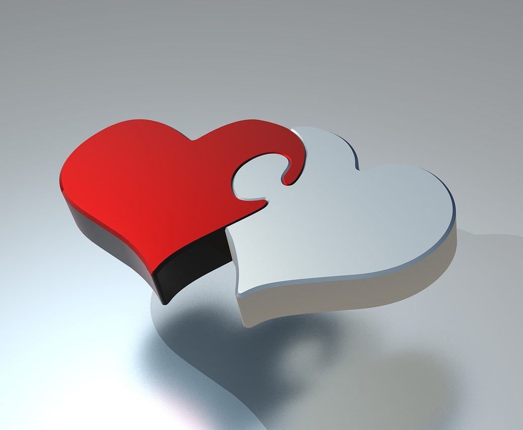 Two interlocking heart-shaped puzzle pieces, one red and one gray, symbolizing love and connection.