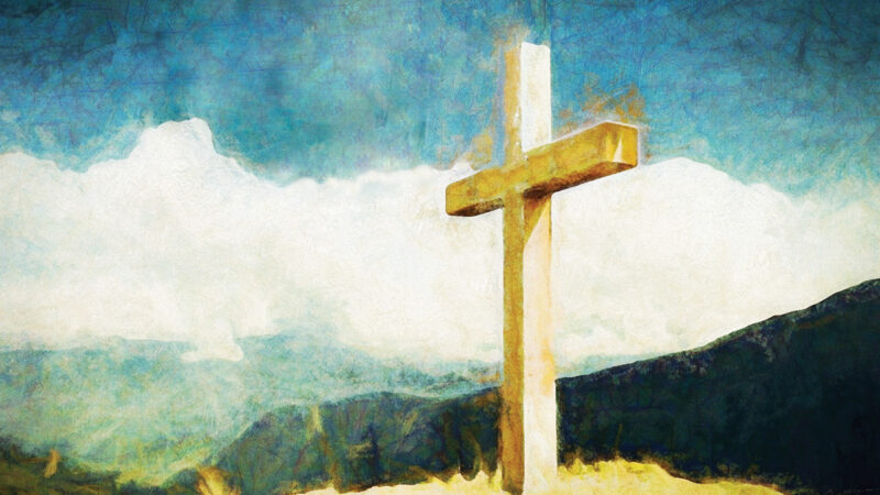 Golden cross on a hill with blue sky background, symbolizing faith and spirituality.