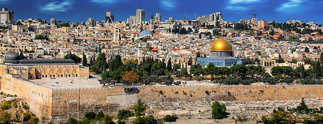 Panoramic view of Jerusalem's Old City featuring the Dome of the Rock and ancient architecture under a blue sky.