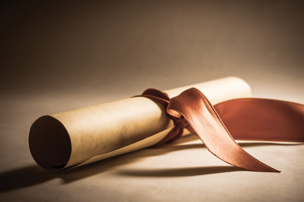 Scroll tied with a red ribbon on a soft-lit background, symbolizing achievement or a special occasion.