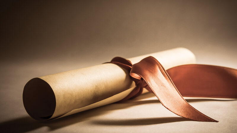 Scroll tied with a red ribbon on a soft-lit background, symbolizing achievement or a special occasion.