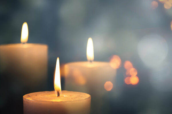 Three lit candles with a soft, blurred background, creating a warm, peaceful ambiance.