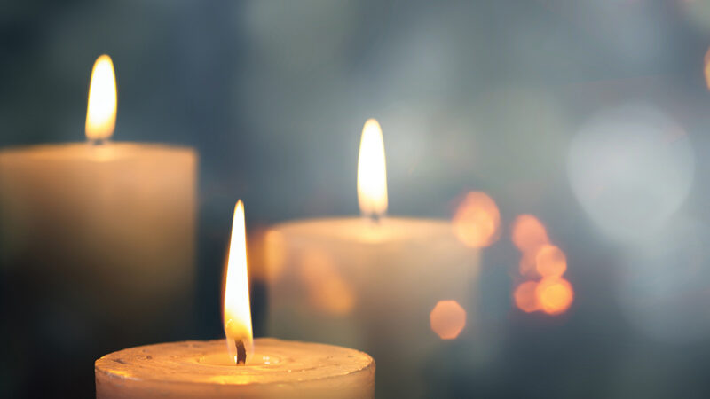 Three lit candles with a soft, blurred background, creating a warm, peaceful ambiance.