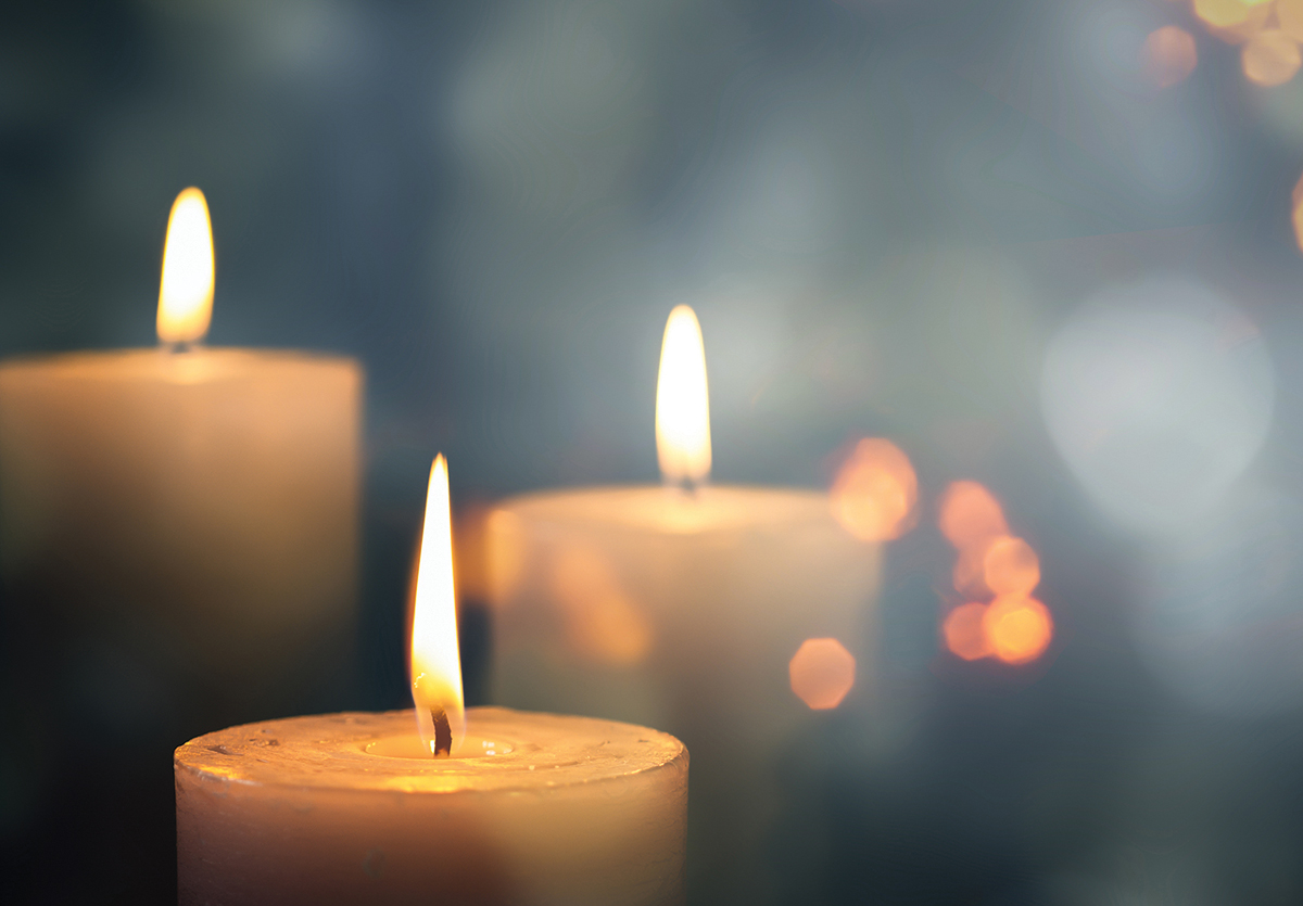 Three lit candles with a soft, blurred background, creating a warm, peaceful ambiance.