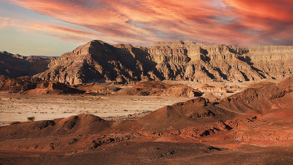 Stunning desert landscape with rocky mountains and vibrant sunset sky, ideal for nature and travel imagery.