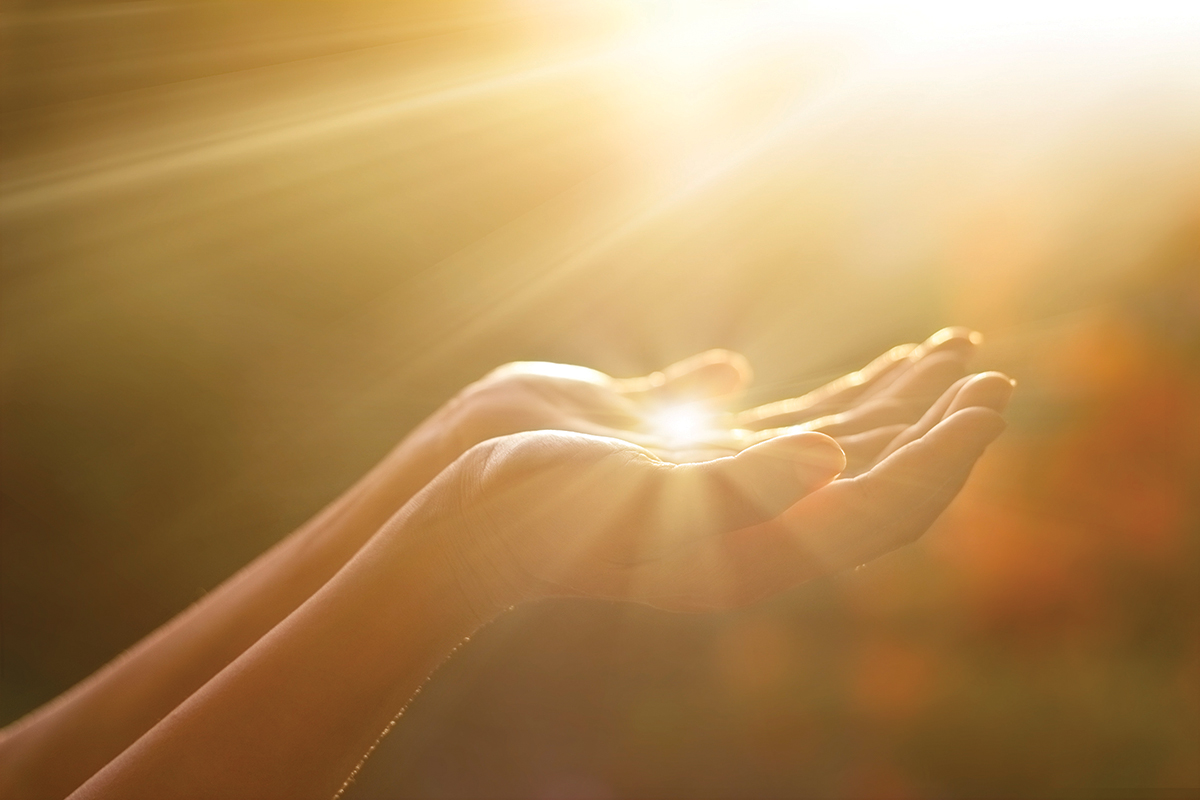 Hands reaching towards sunlight, conveying hope and spirituality in a bright, golden ambiance.
