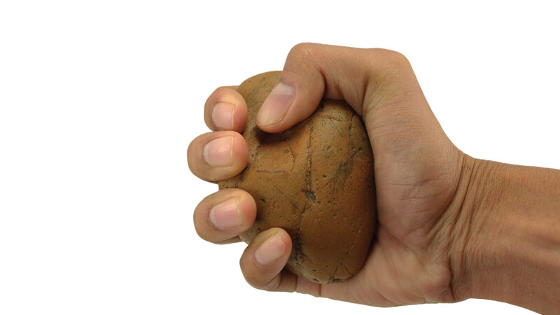 Hand squeezing stress ball, showcasing grip strength exercise on a white background.